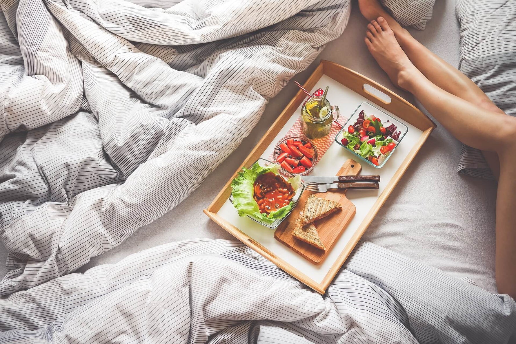 woman’s legs in bed near breakfast