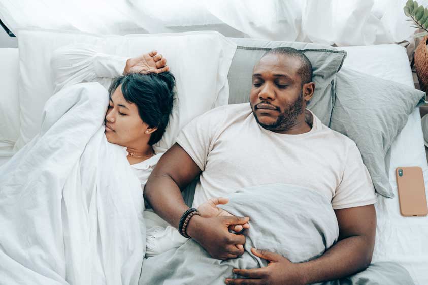 A couple sleeping in bed holding hands
