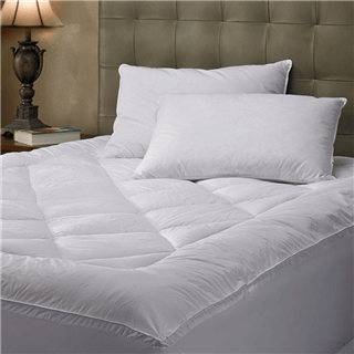 A plush mattress pad with a couple of pillows on top