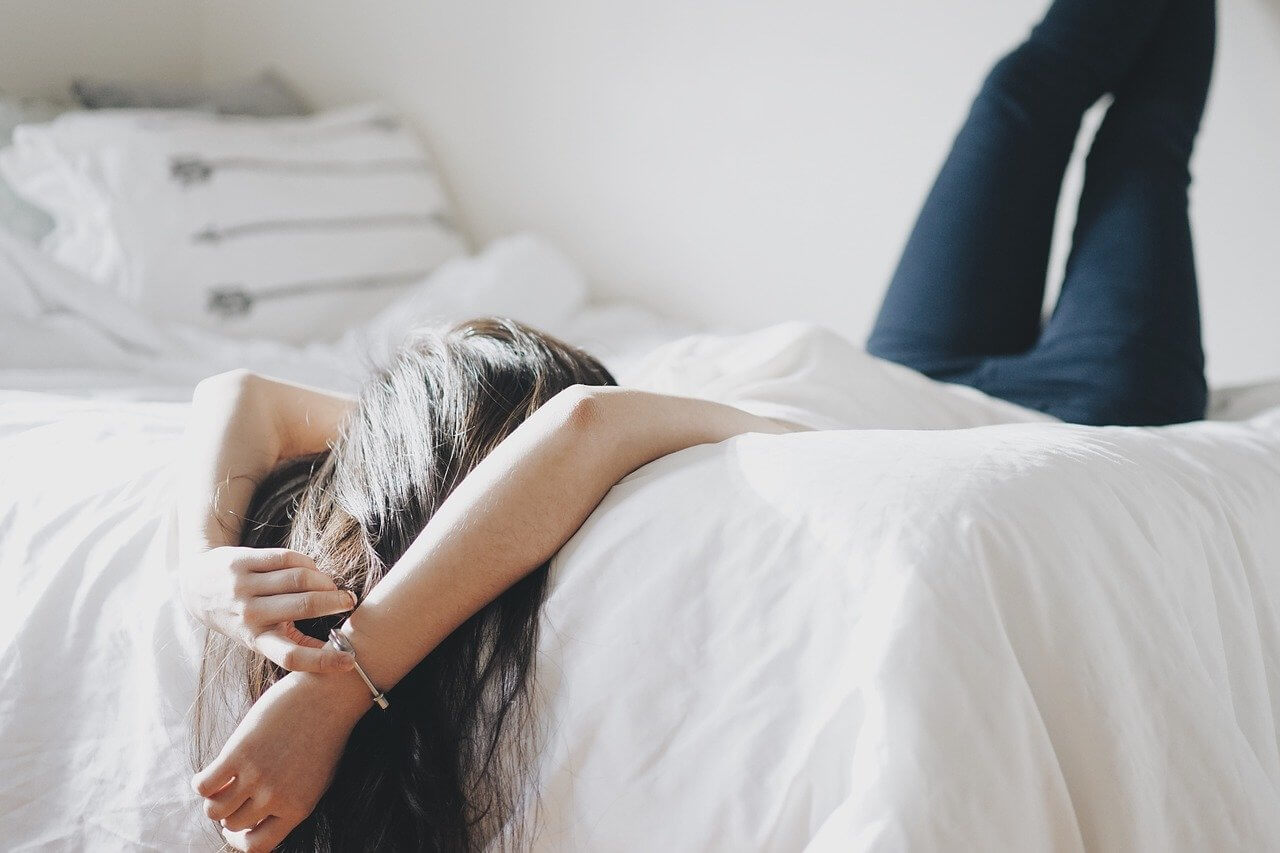 woman lying across comforter with feminine bedroom decor
